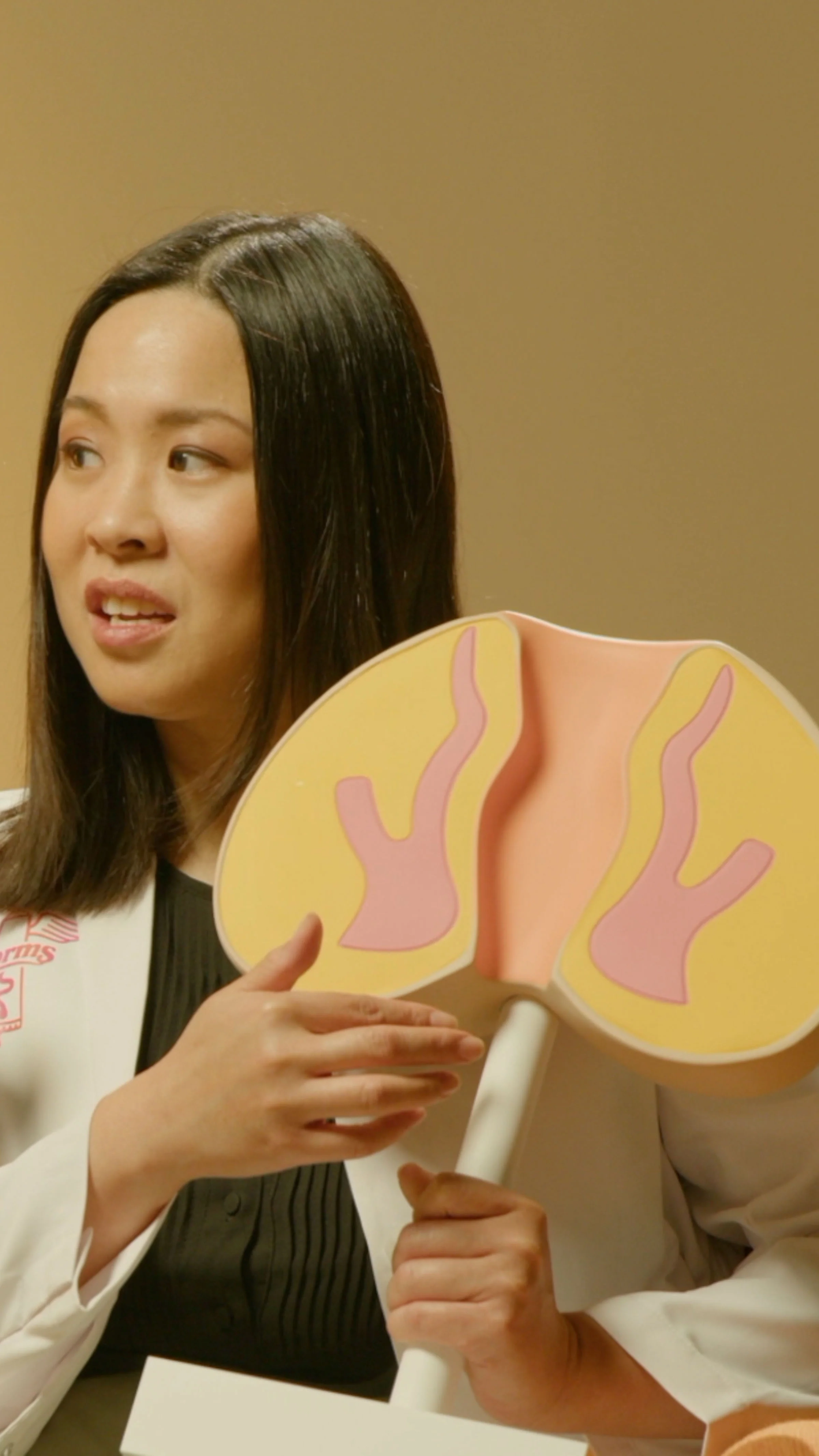 Woman holding a model of a human rear against a beige background. What are hemorrhoids?