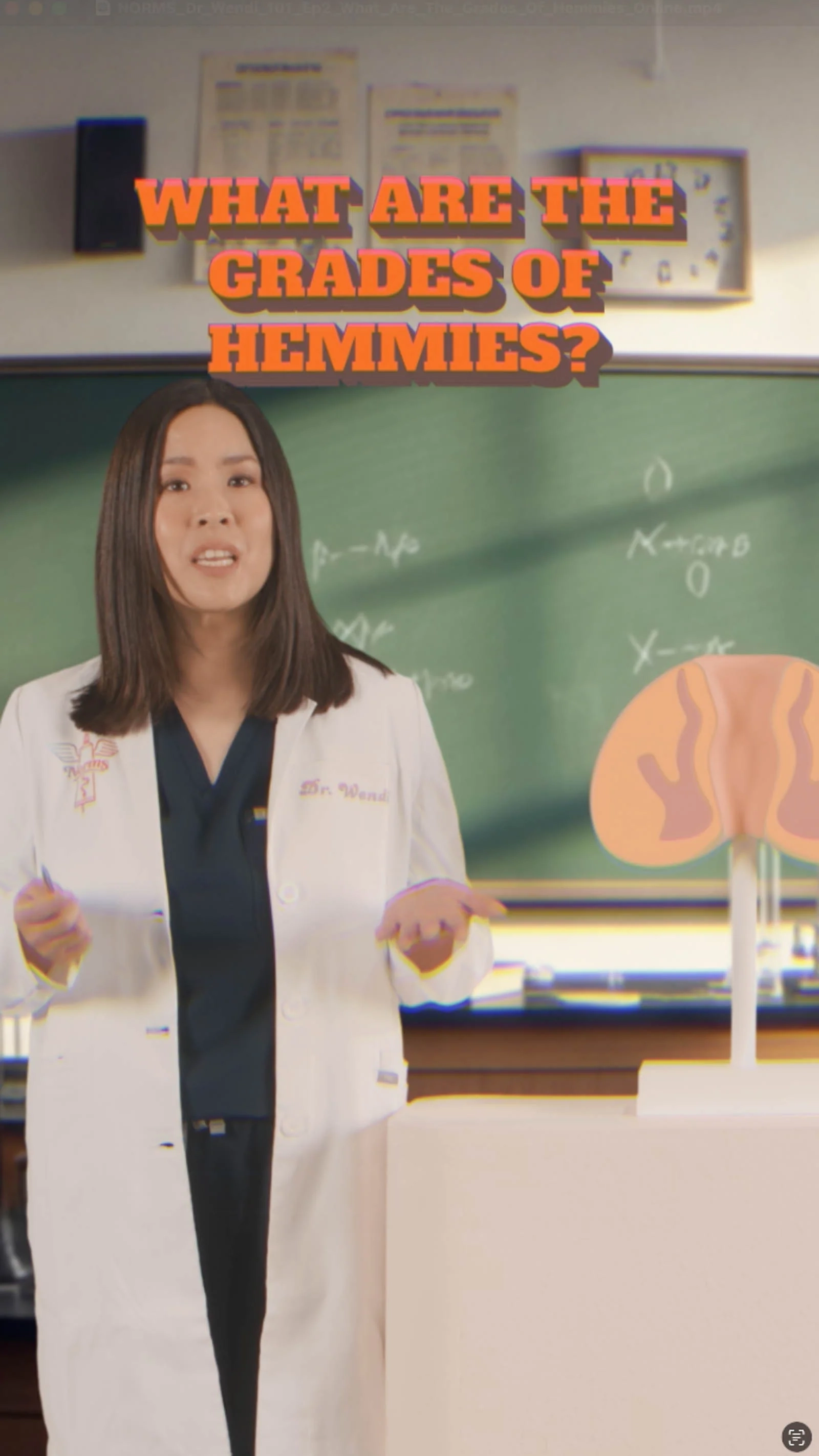 Woman in a white lab coat standing in front of a chalkboard with educational content about hemorrhoid treatment
